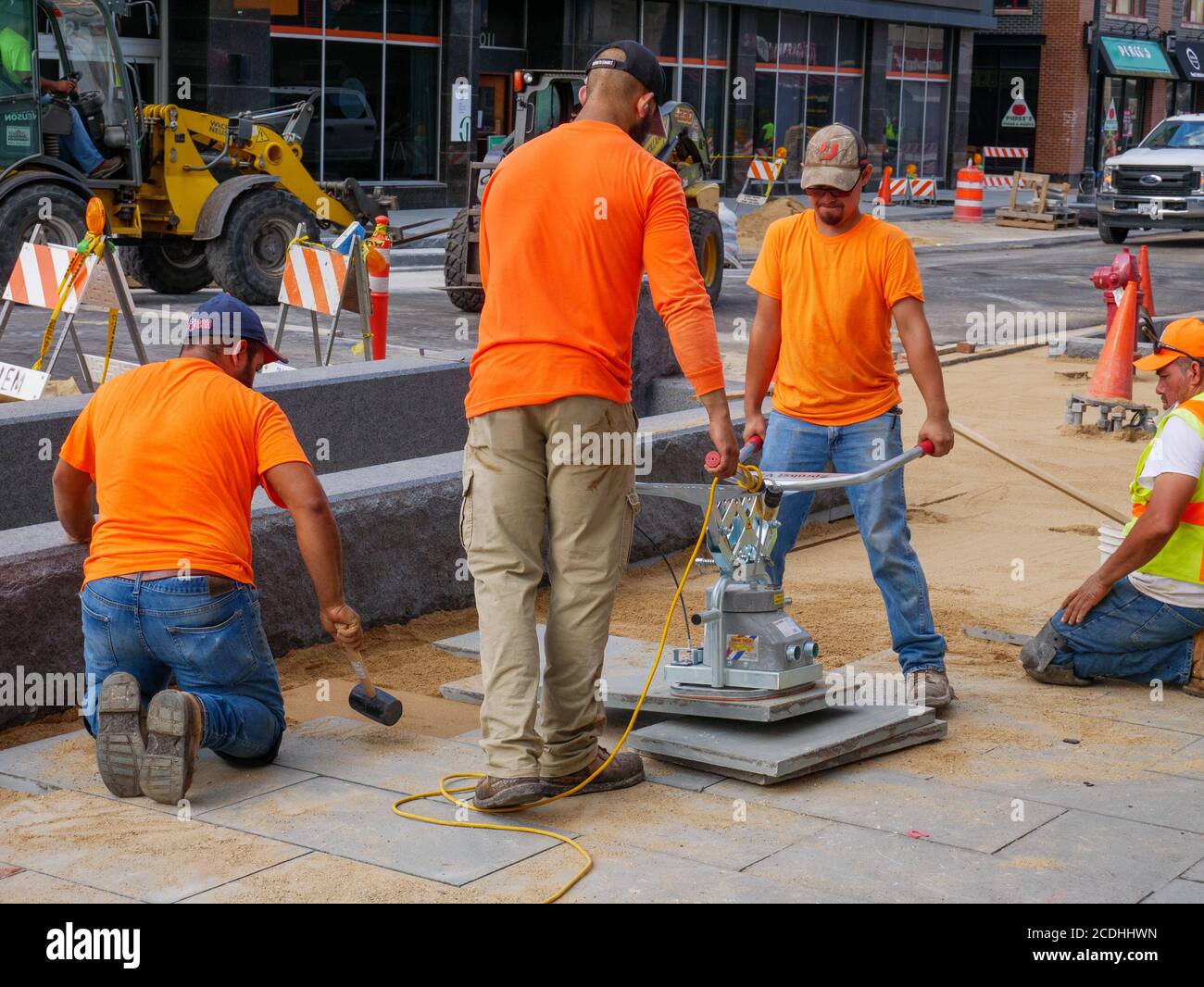 Construction workers using electric suction lifter to place pavement blocks on Lake Street Reconstruction Project. Oak Park, Illinois. Stock Photo