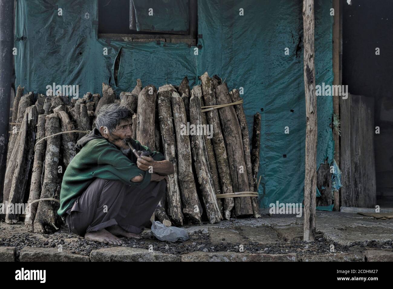 Khasi tribal man is smoking hand made pipe infront of his home at Cherrapunji [Meghalaya, India] Stock Photo