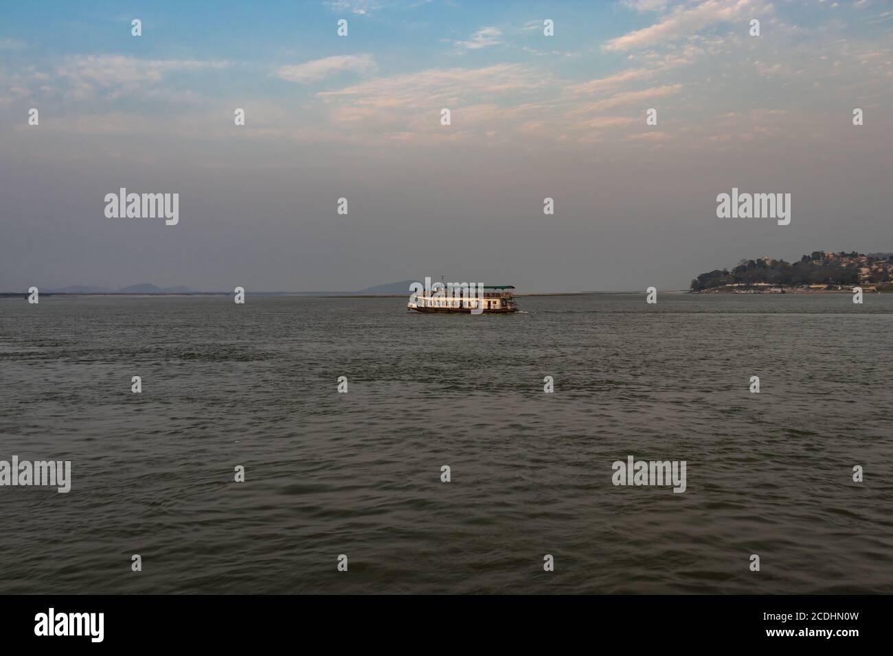 ship heading towards river island at dusk image is taken at peacock island guwahati assam india. it is showing the serene beauty of nature at dusk. Stock Photo