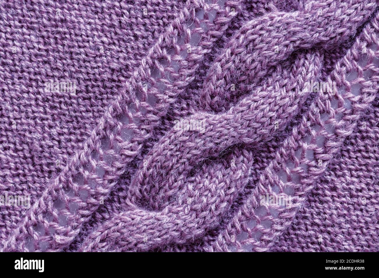Openwork pattern knitted with needles from pink wool yarn. Stock Photo
