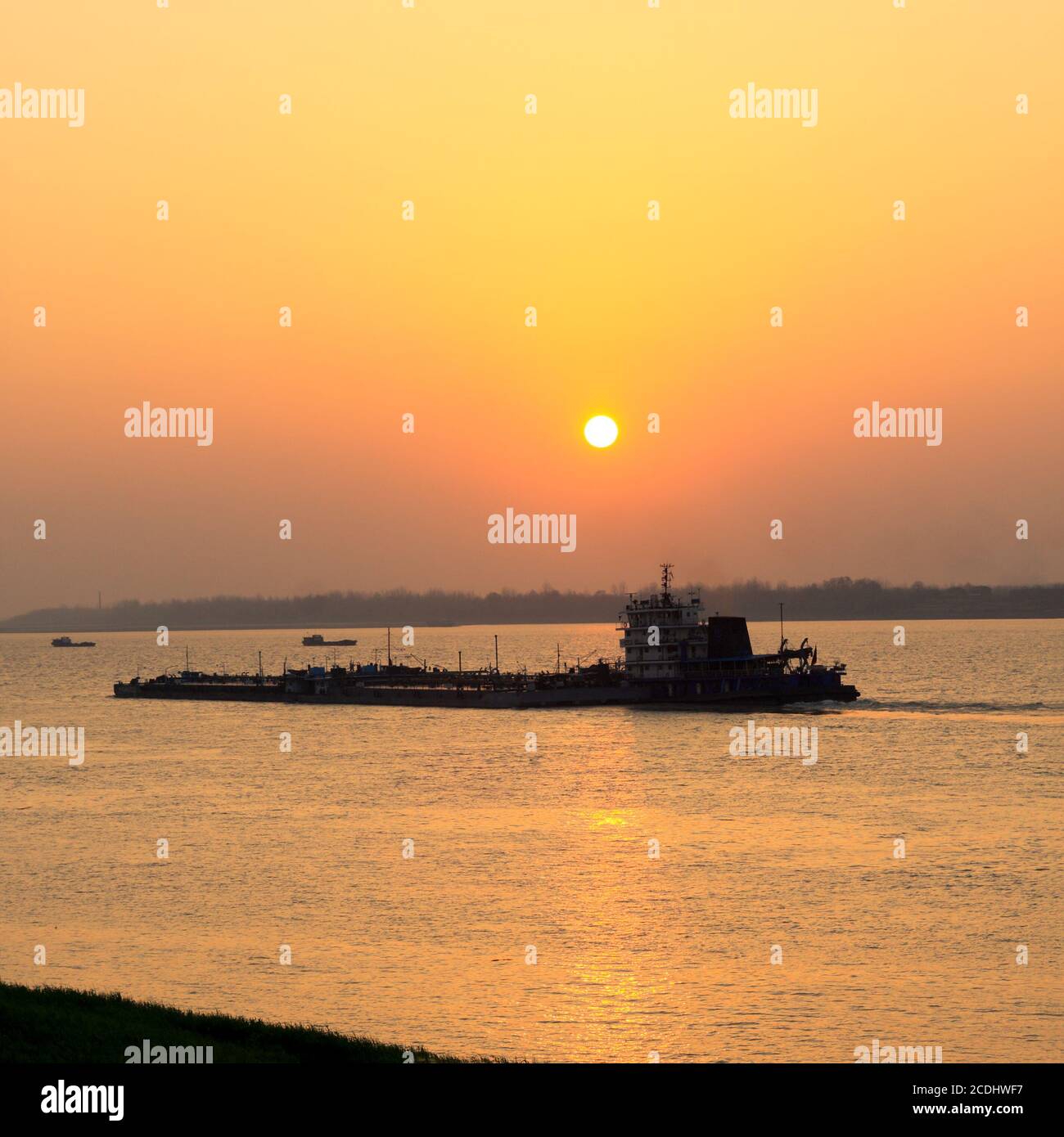cargo ship sailing at sunset Stock Photo