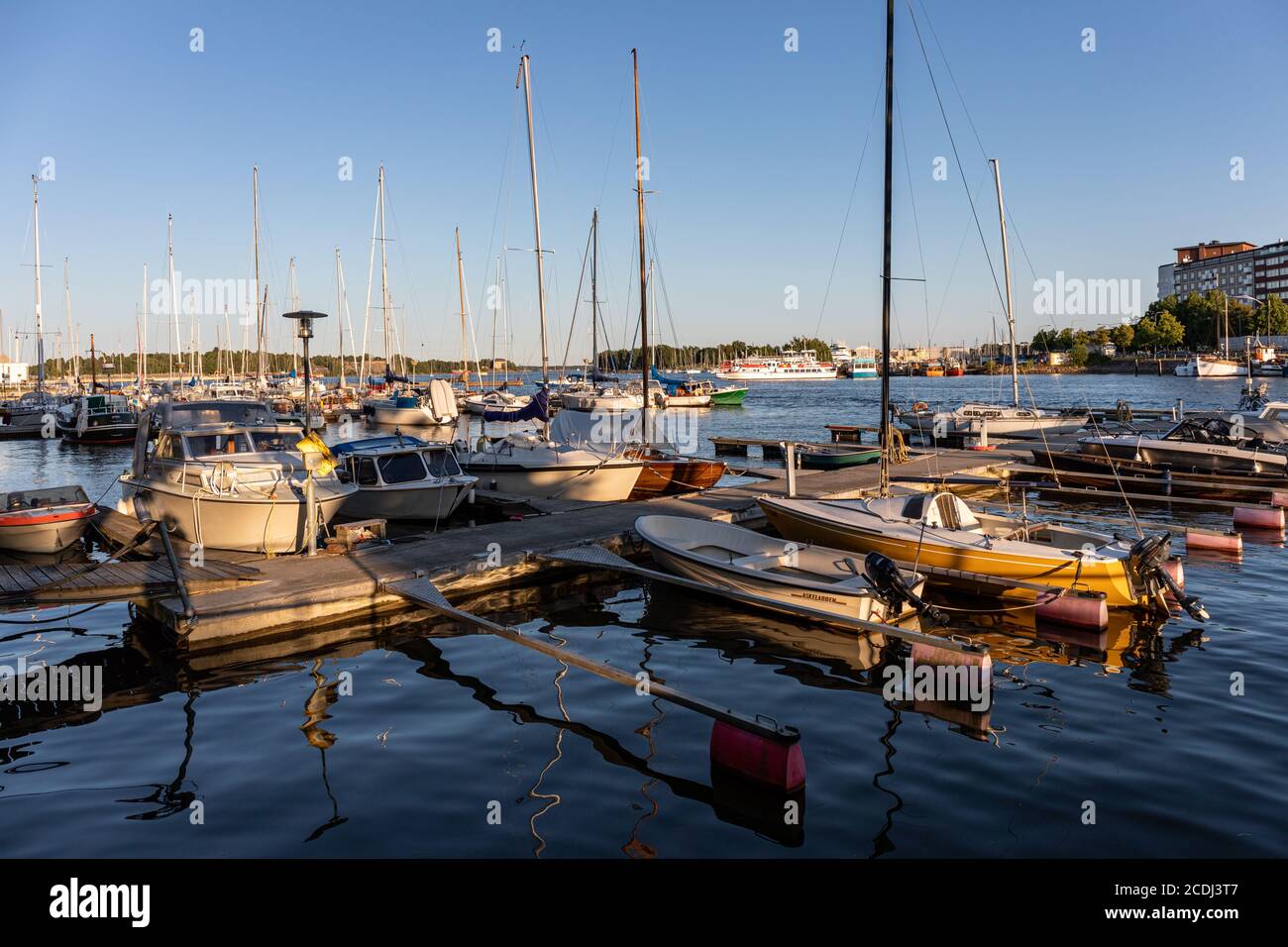 Sailing boats and motorboats basking in the evening sun in Merihaka district of Helsinki, Finland Stock Photo