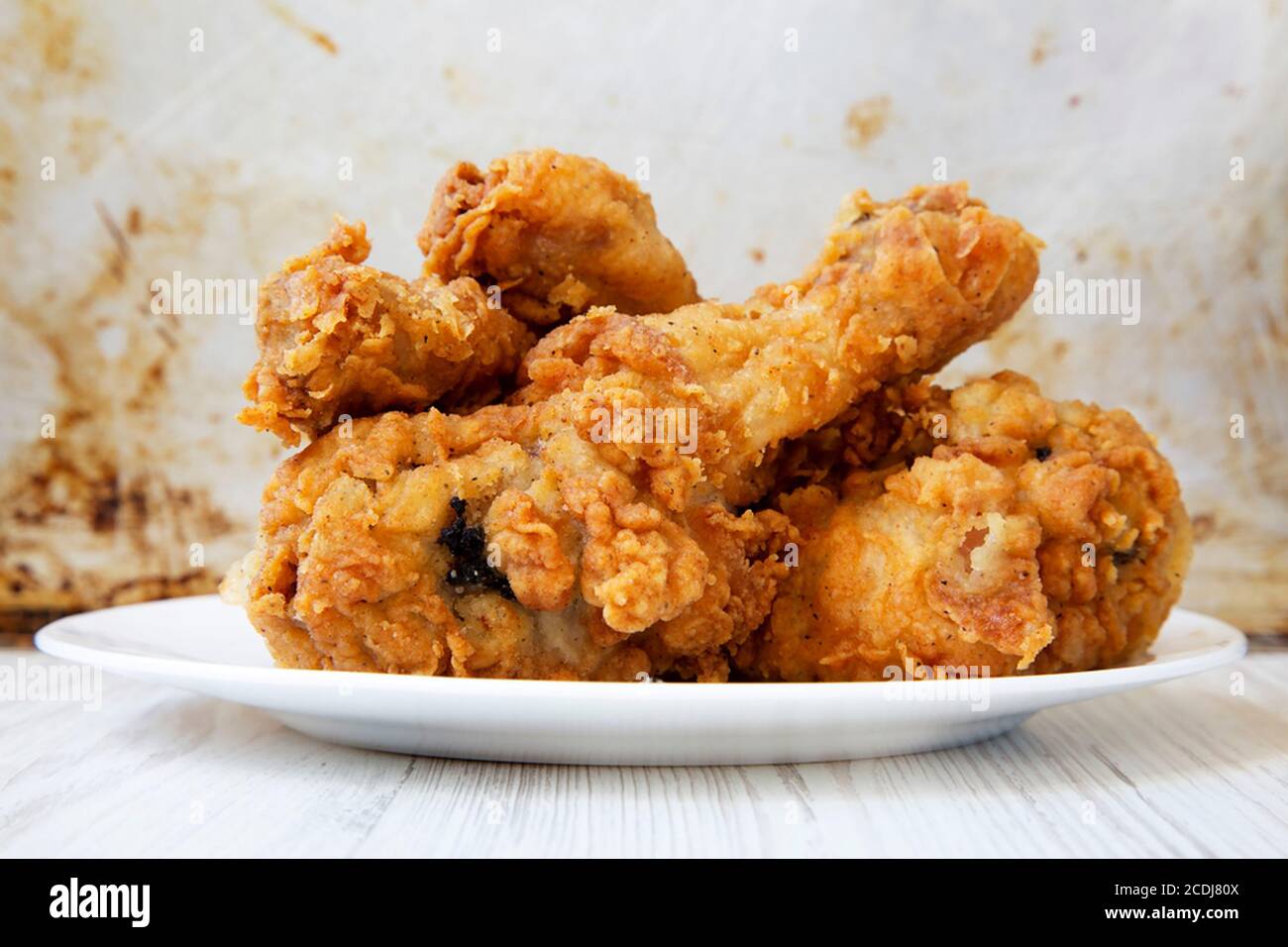 Fried chicken drumsticks on a white round plate, closeup. Side view ...