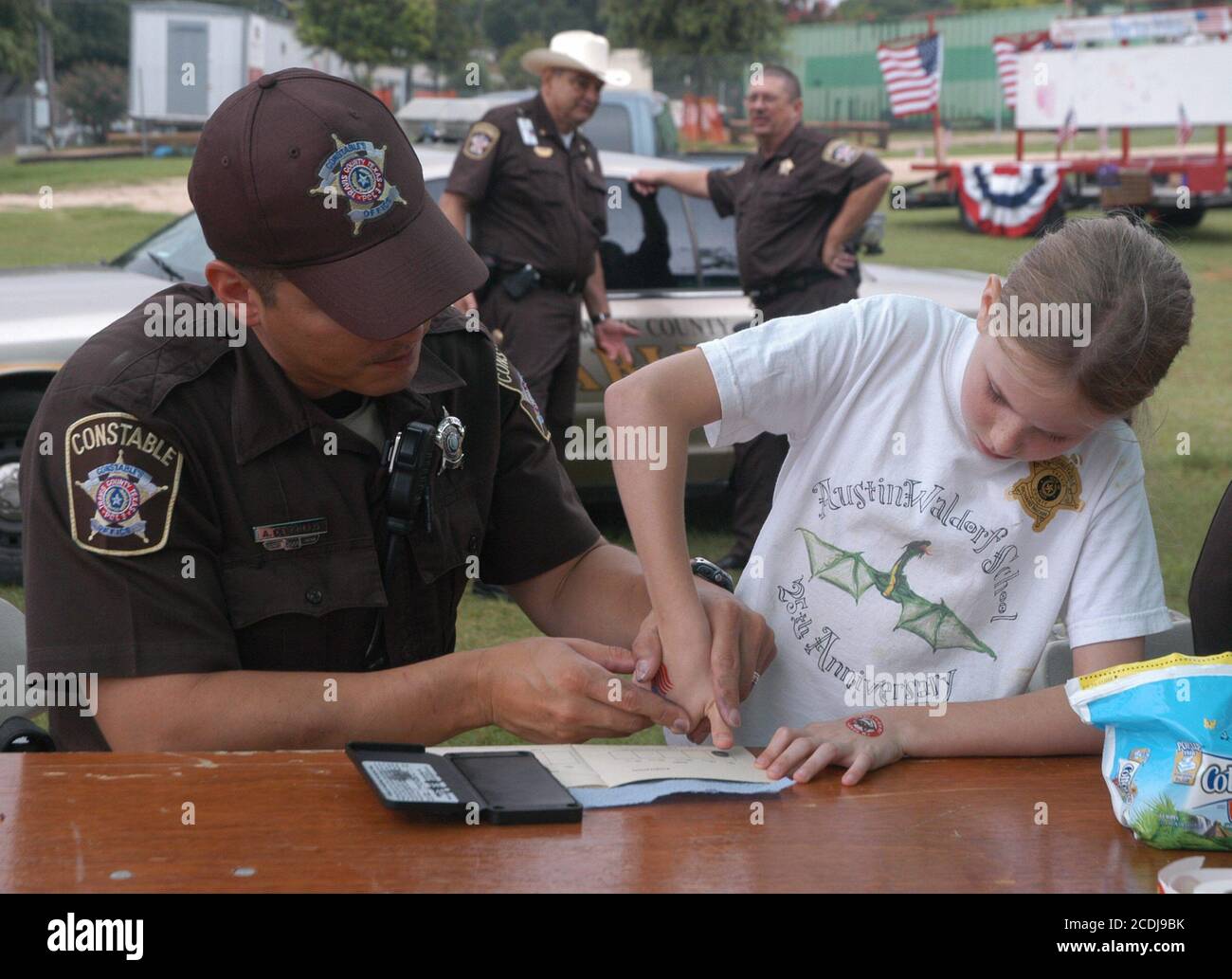 Austin, TX July 4, 2007:  A Hispanic Travis County constable fingerprints a 10-year old girl as part of a crime prevention and safety awareness campaign at a neighborhood Fourth of July celebration.  Editorial use only.    ©Bob Daemmrich Stock Photo