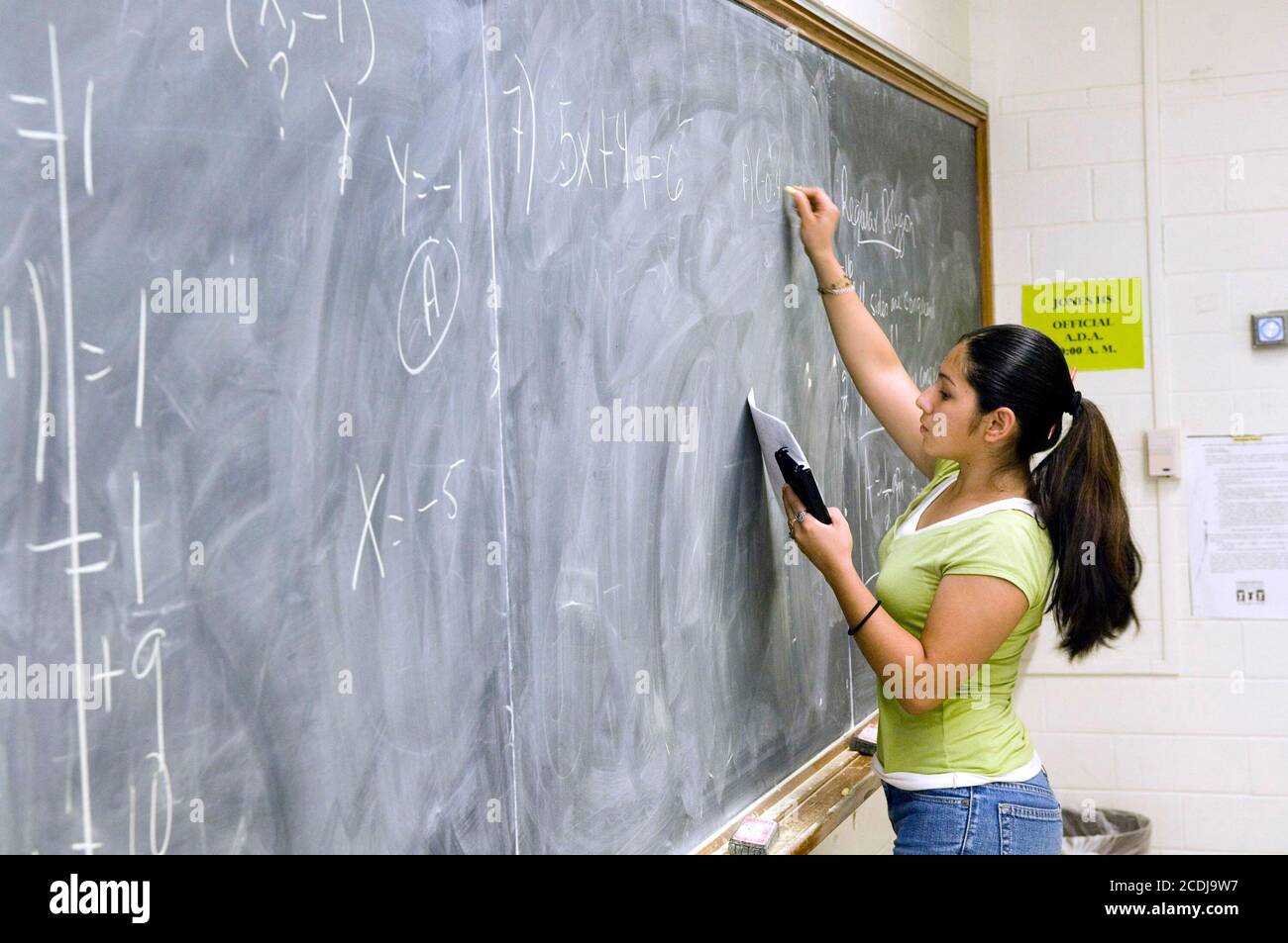 Houston, TX May 17, 2007: Hispanic female algebra student writes out a problem on the board at Jesse Jones High School,  a traditional inner-city high school with 50-50 mix of African-American and Hispanic students.  ©Bob Daemmrich Stock Photo