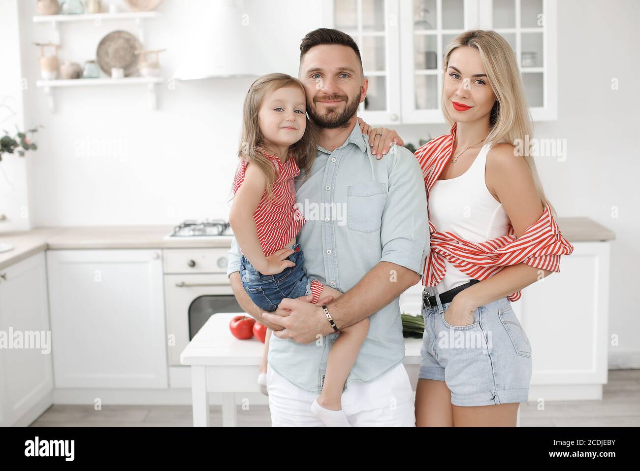 Happy family with daughter in casual wear at home in kitchen  Stock Photo