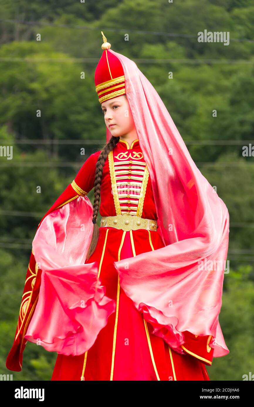 DAKHOVSKY, RUSSIA - JULY 25 2015: The girl the Muslim in a beautiful red national Adyghe suit against mountains. The Festival 'Lago-Naki: Kunatskaya' Stock Photo