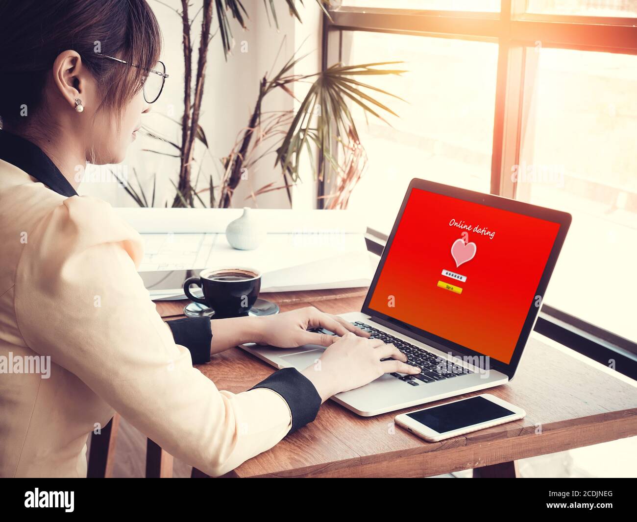 online love concept: office girl using online dating website on a laptop display, hardwood desktop and stationery on background Stock Photo