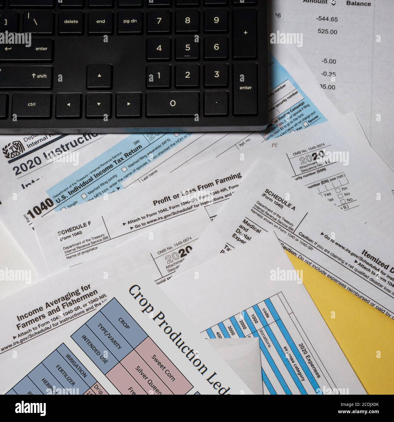2020 IRS tax forms and personal papers on a desktop with a computer keyboard number pad above
