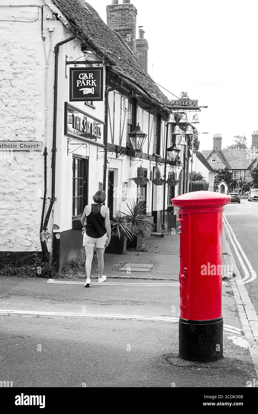 Red royal mail post box outside the black and white six bells pub in the Oxfordshire market town of Thame Stock Photo