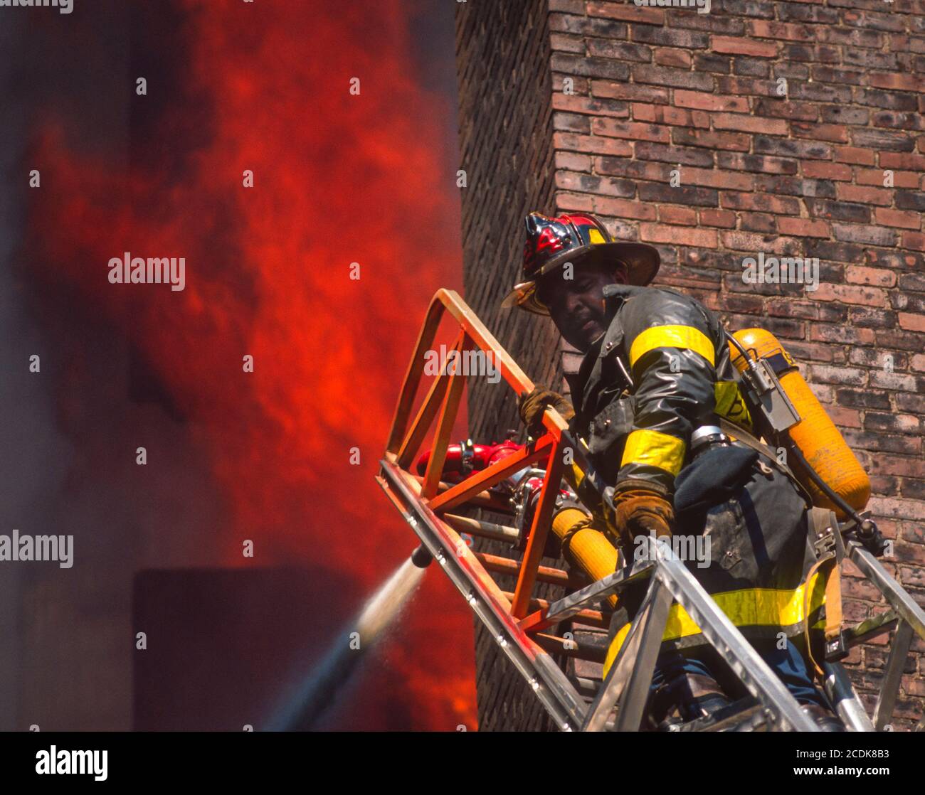 BOSTON, MASSACHUSETTS, USA - Firefighter on ladder during building fire. Stock Photo