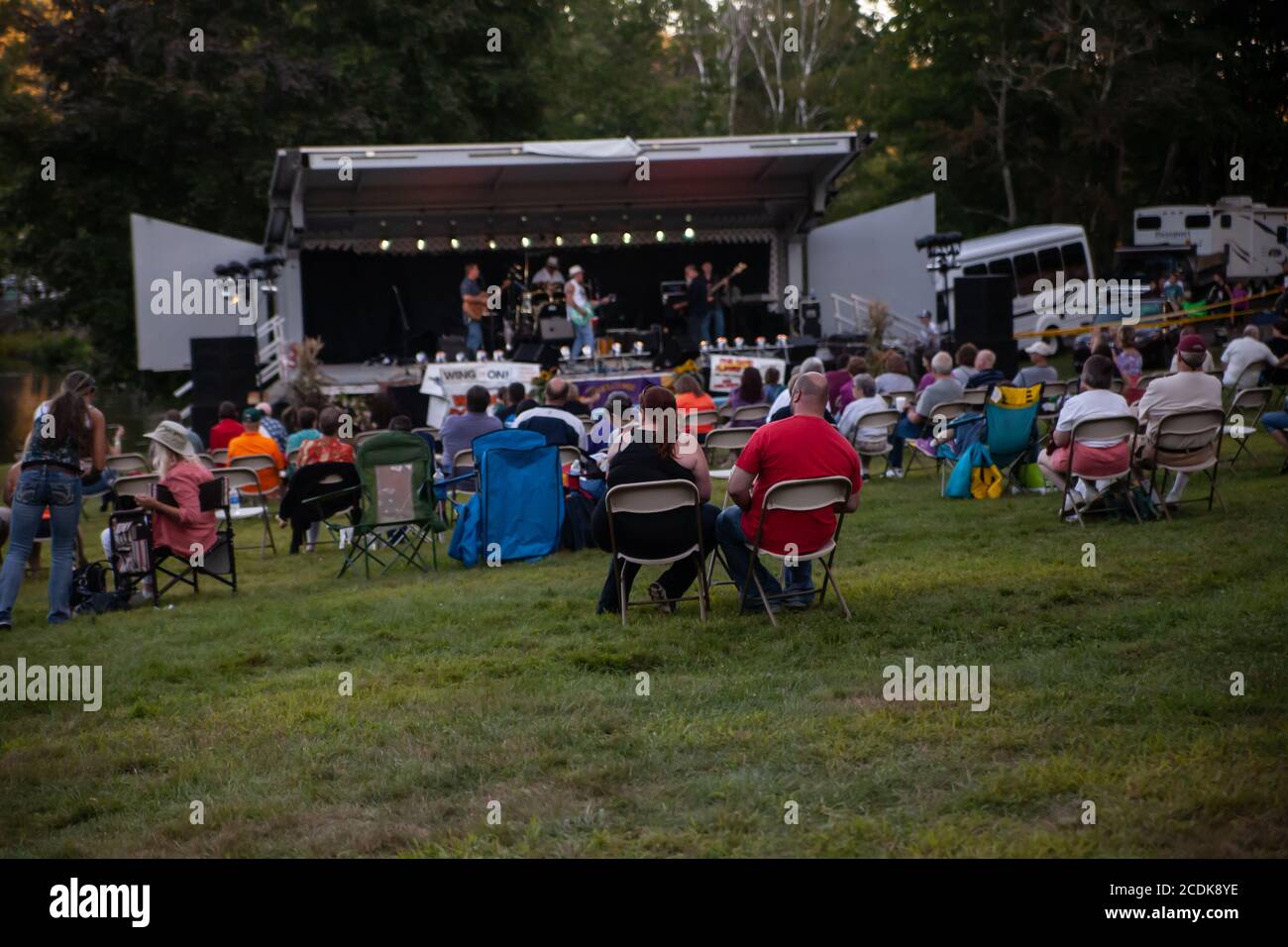 The rock band is performing on the stage, and the audience is watching the performance during a country fair. Stock Photo