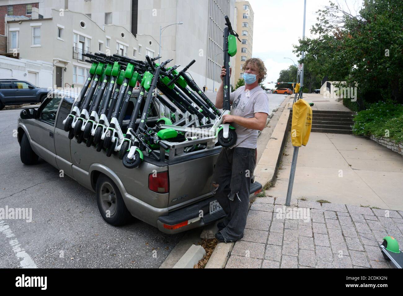 A contract gig worker places chargedup Lime scooters on a street