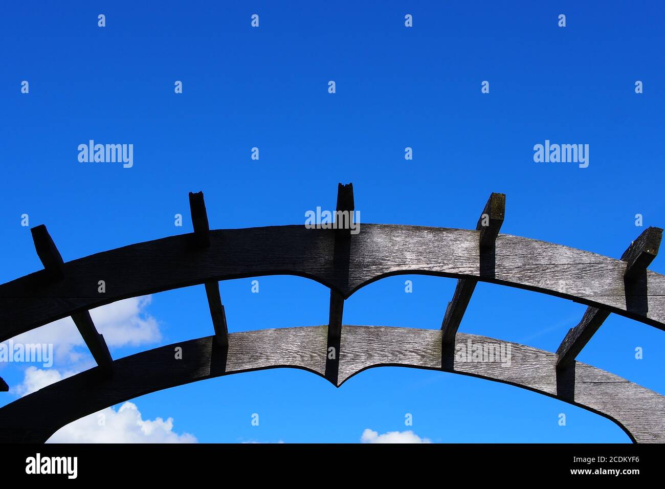 Black painted wooden garden archway, half in sun half in shade, against a clear blue sky at the ornamental gardens, Ottawa, Ontario, Canada. Stock Photo