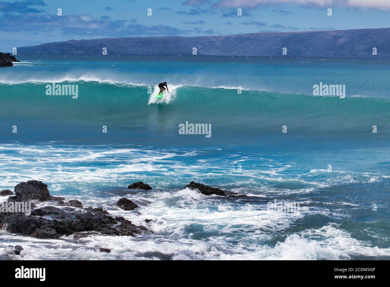 Lone high energy silhouetted surfer riding a big wave on Maui. Stock Photo