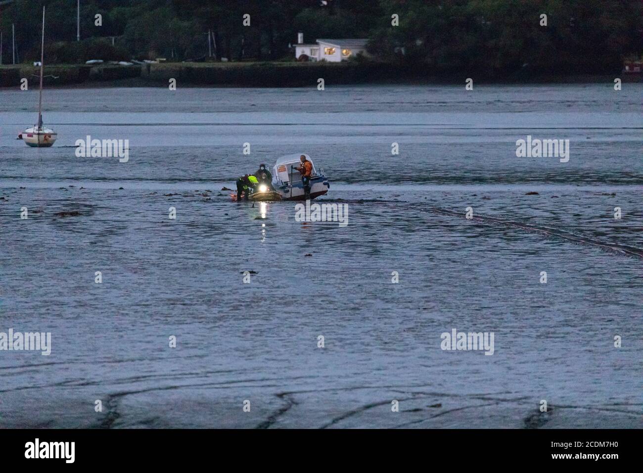 Rescue of Hire Boat boat aground in Restonguet Creek, Cornwall.  High tide is not due to float them off until 03AM and bad weather is expected. Stock Photo