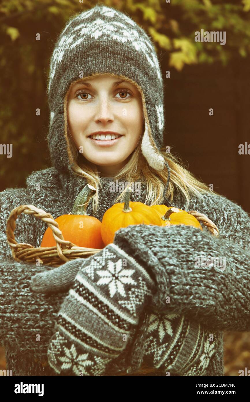 Young woman holding a basket of pumpkins Stock Photo