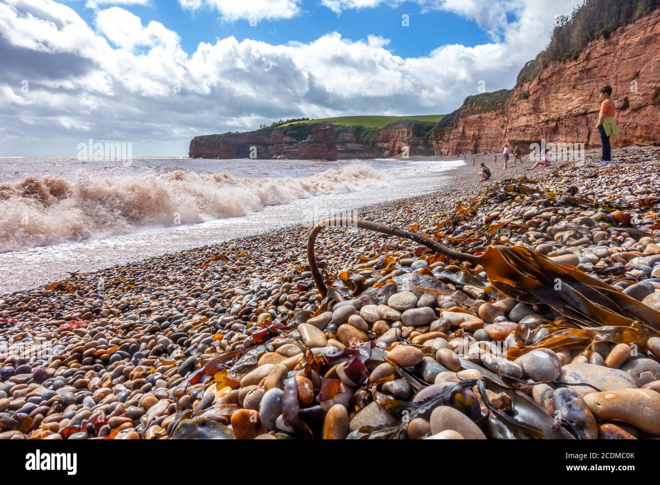 Waves roll onto the beach at Ladram Bay near Exmouth in Devon, England. People are on the beach on holiday. Stock Photo
