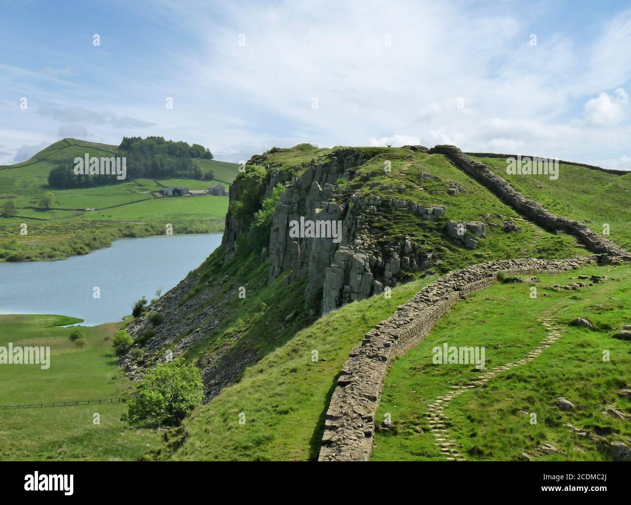 Cirrus clouds in a blue sky advance over Highshield Crags, a dramatic stretch of Hadrian’s Wall in northern England Stock Photo
