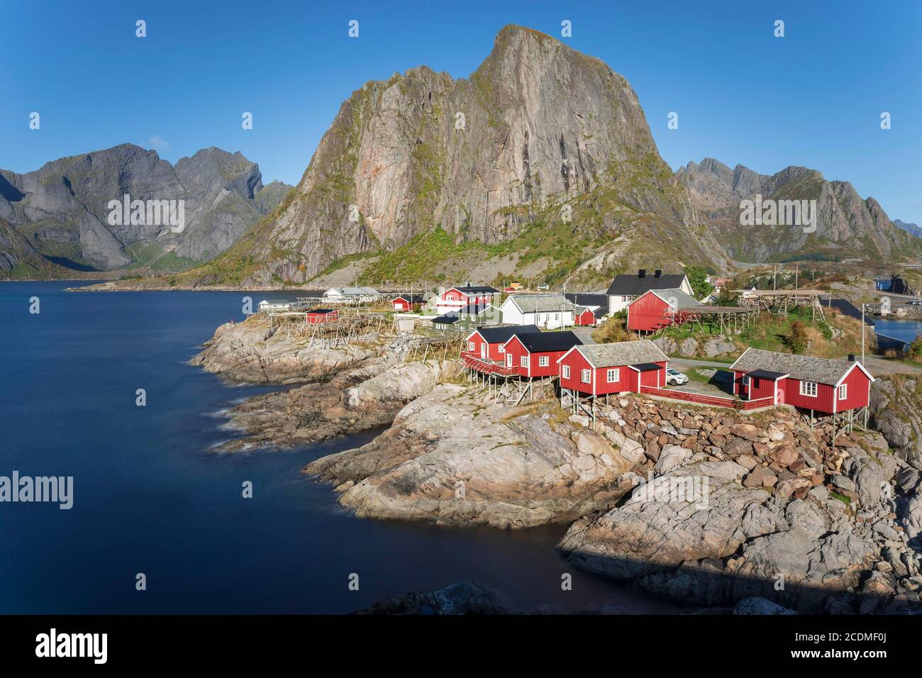 Red wooden houses Rorbu, Rorbu fishermen's cabins, by the Reine Fjord, Reinefjords, behind the mountain range of Festhaeltinten, Hamnoy Stock Photo