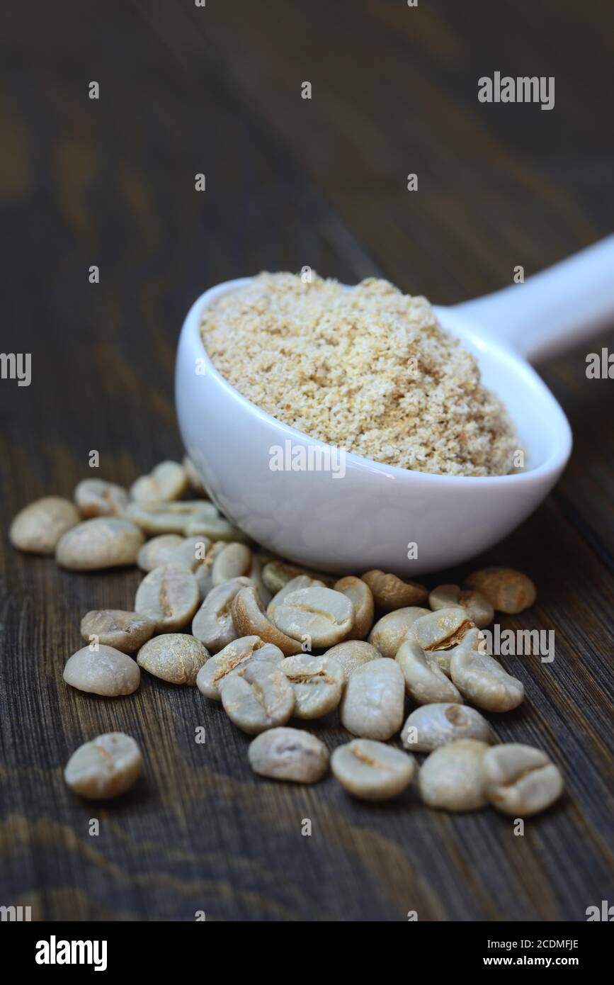 Green coffee beans and unroasted coffee powder in spoon, Germany Stock Photo