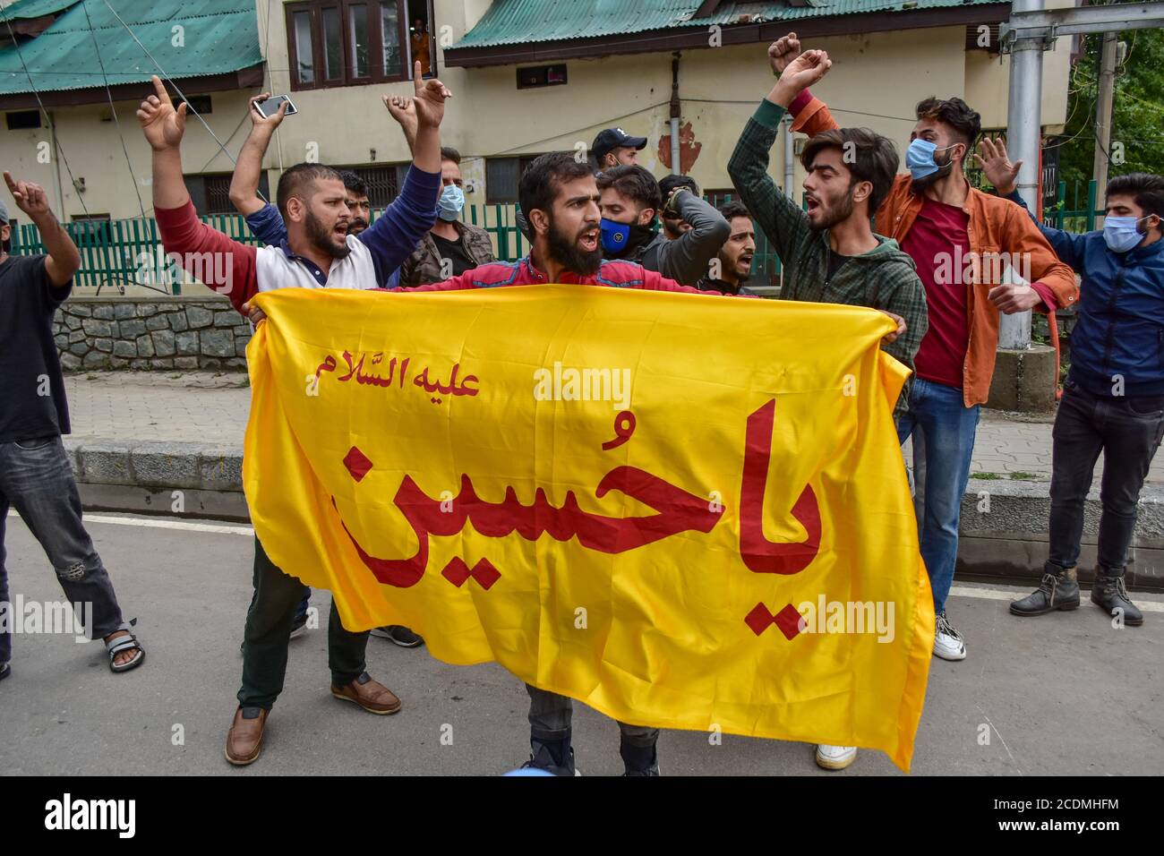 A Kashmiri Shiite Muslim devotee holds a banner while others shout ...