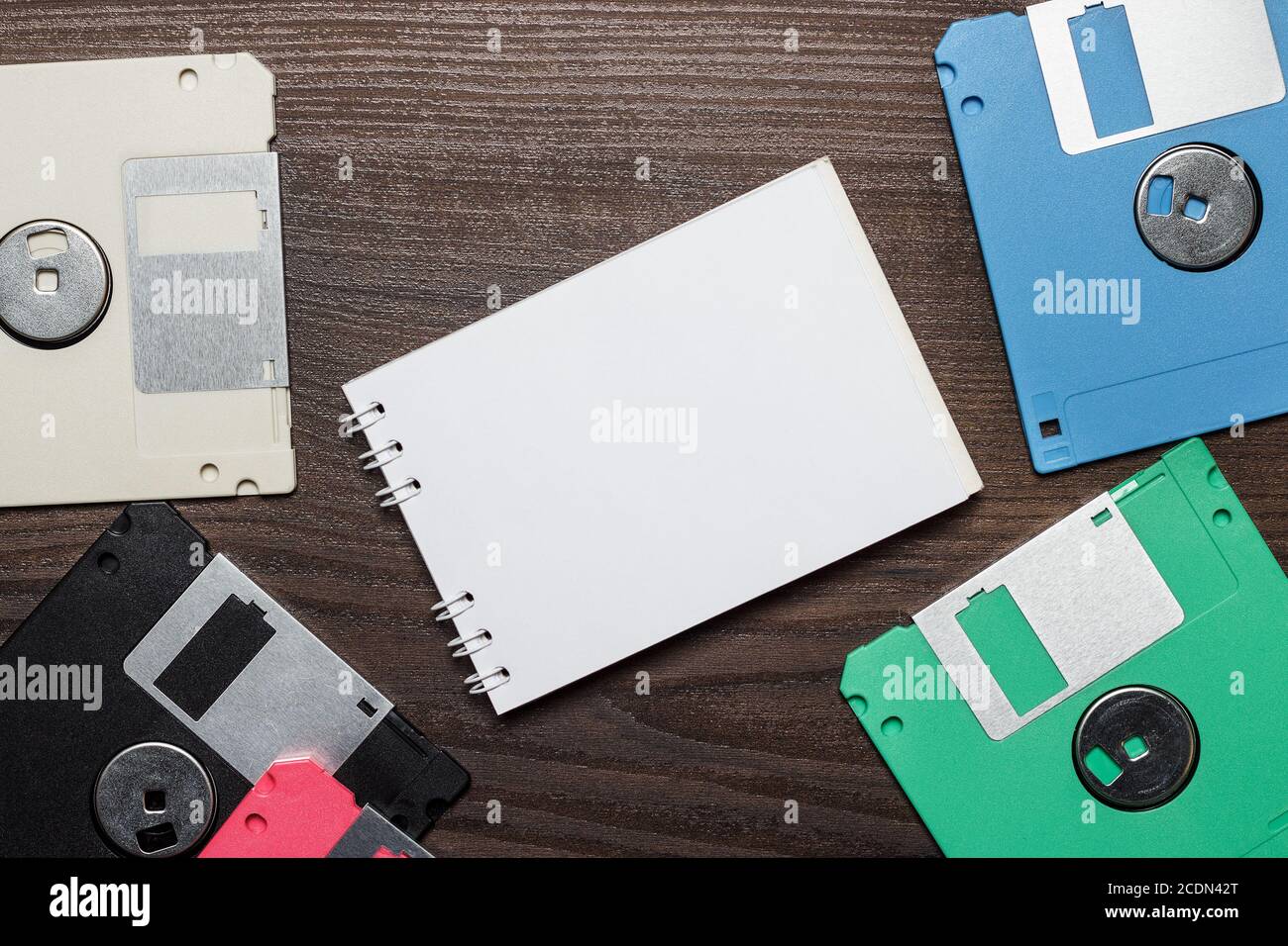 diskettes and blank notebook on wooden background Stock Photo