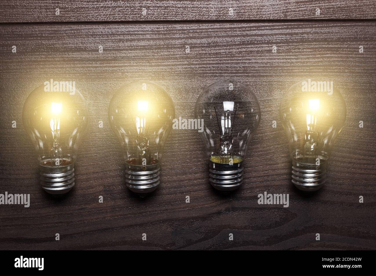 glowing bulbs weak link concept on wooden background Stock Photo