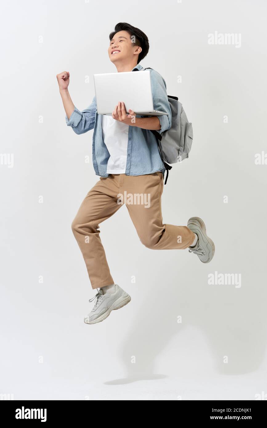 Full length body size of young Asian student man jumping in air using laptop with backapck isolated over white color background Stock Photo