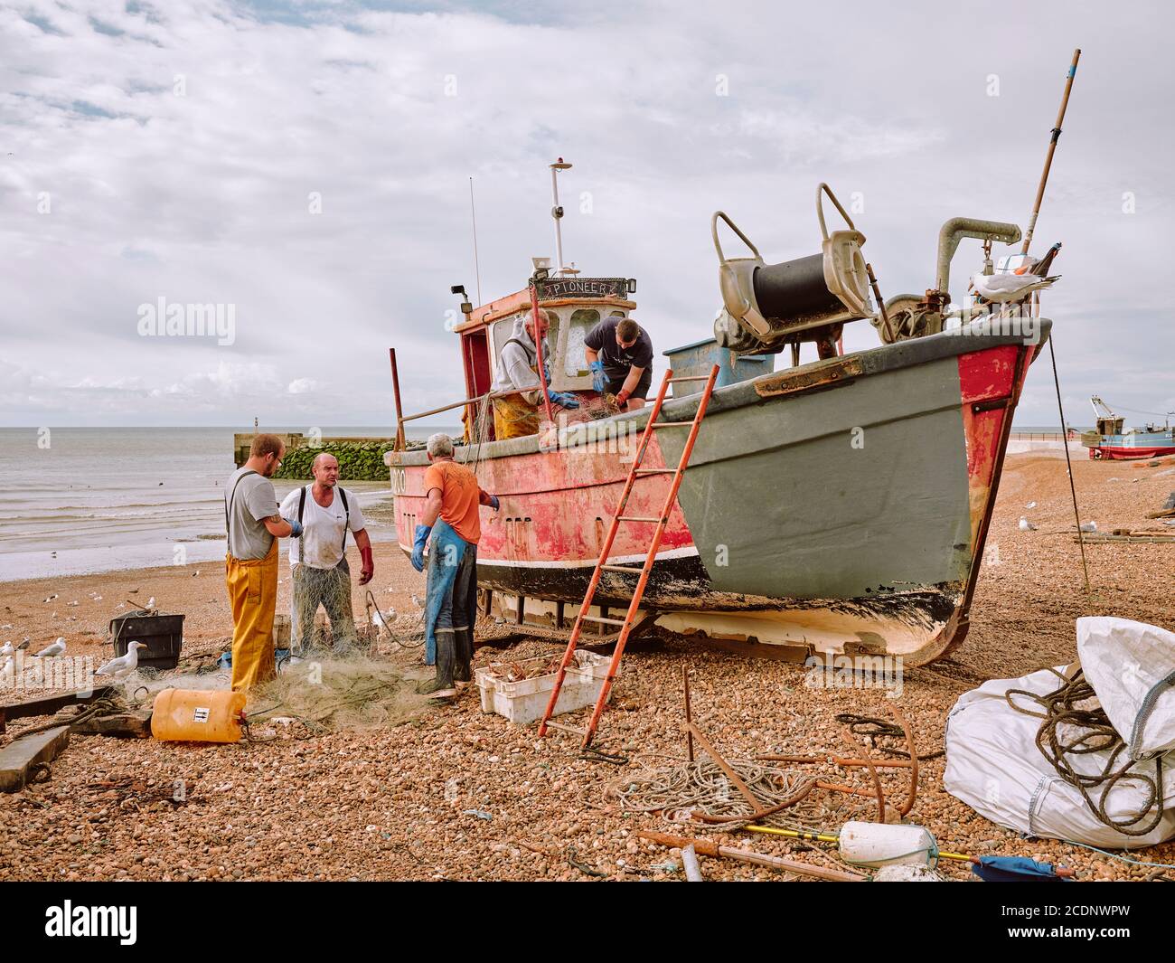 Fishermen landing their catch of Spider Crabs on The Stade shingle beach in Hastings Old Town, East Sussex England UK - Crab fishing boat Stock Photo