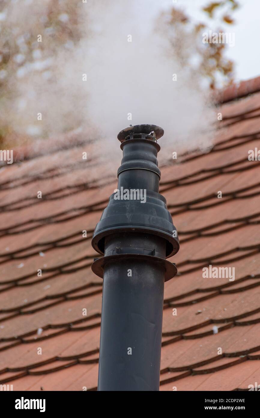 Old smoking chimney on a tile roof Stock Photo