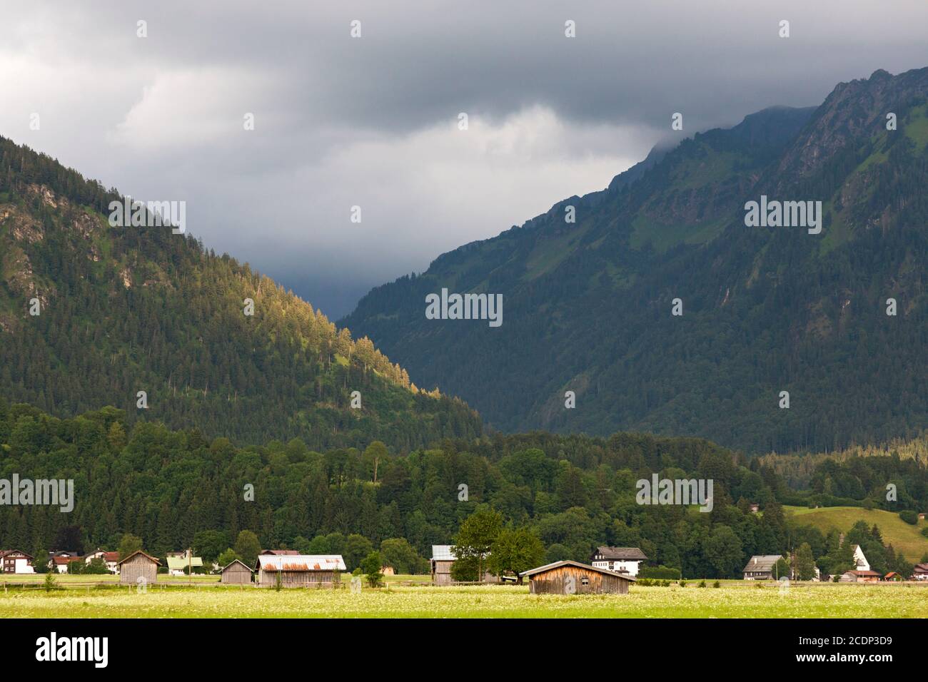 Scheune, Häuser, bewaldete Berge, tiefliegende Wolken Stock Photo