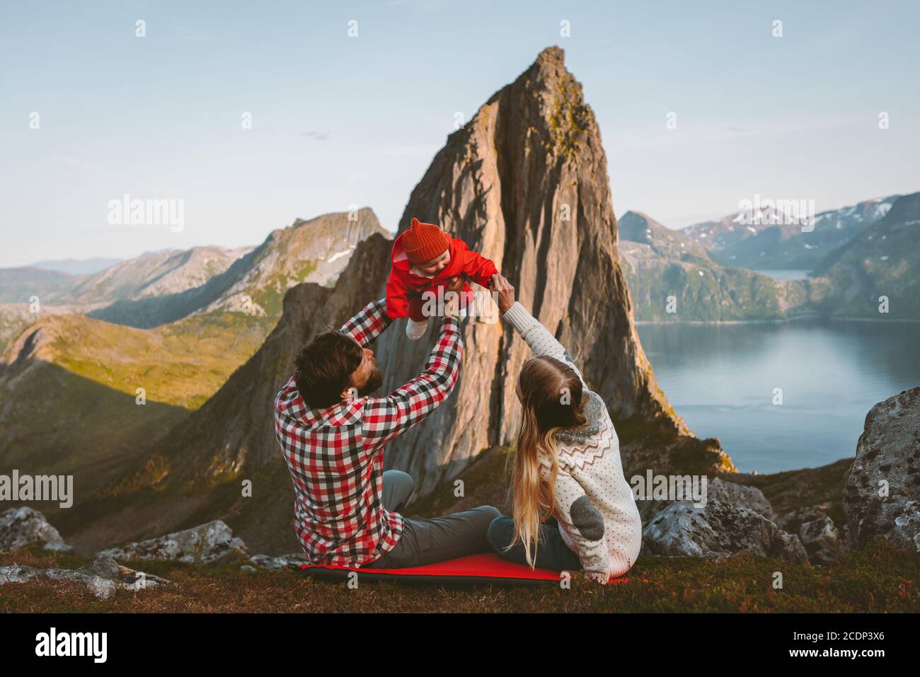 Family parents mother and father with baby playing outdoor active healthy lifestyle camping with Segla mountain view eco tourism in Norway man and wom Stock Photo