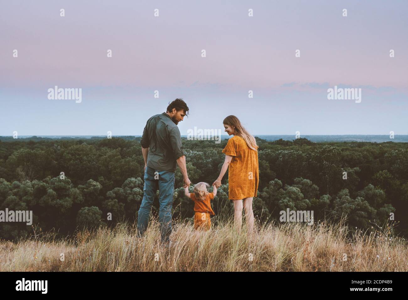 Family parents mother and father with baby holding hands walking outdoor together healthy lifestyle rural nature forest landscape Stock Photo