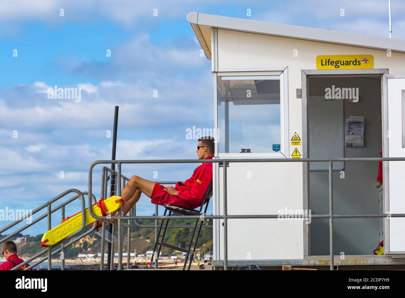 Bournemouth, Dorset UK. 29th August 2020. UK weather: cool and breezy with the odd glimmer of sunshine. Few people at Bournemouth beaches as yet for the start of the long Bank Holiday weekend - not the usual Bank Holiday crowds heading to the seaside!  RNLI Lifeguards on patrol at Lifeguards kiosk hut. Credit: Carolyn Jenkins/Alamy Live News Stock Photo