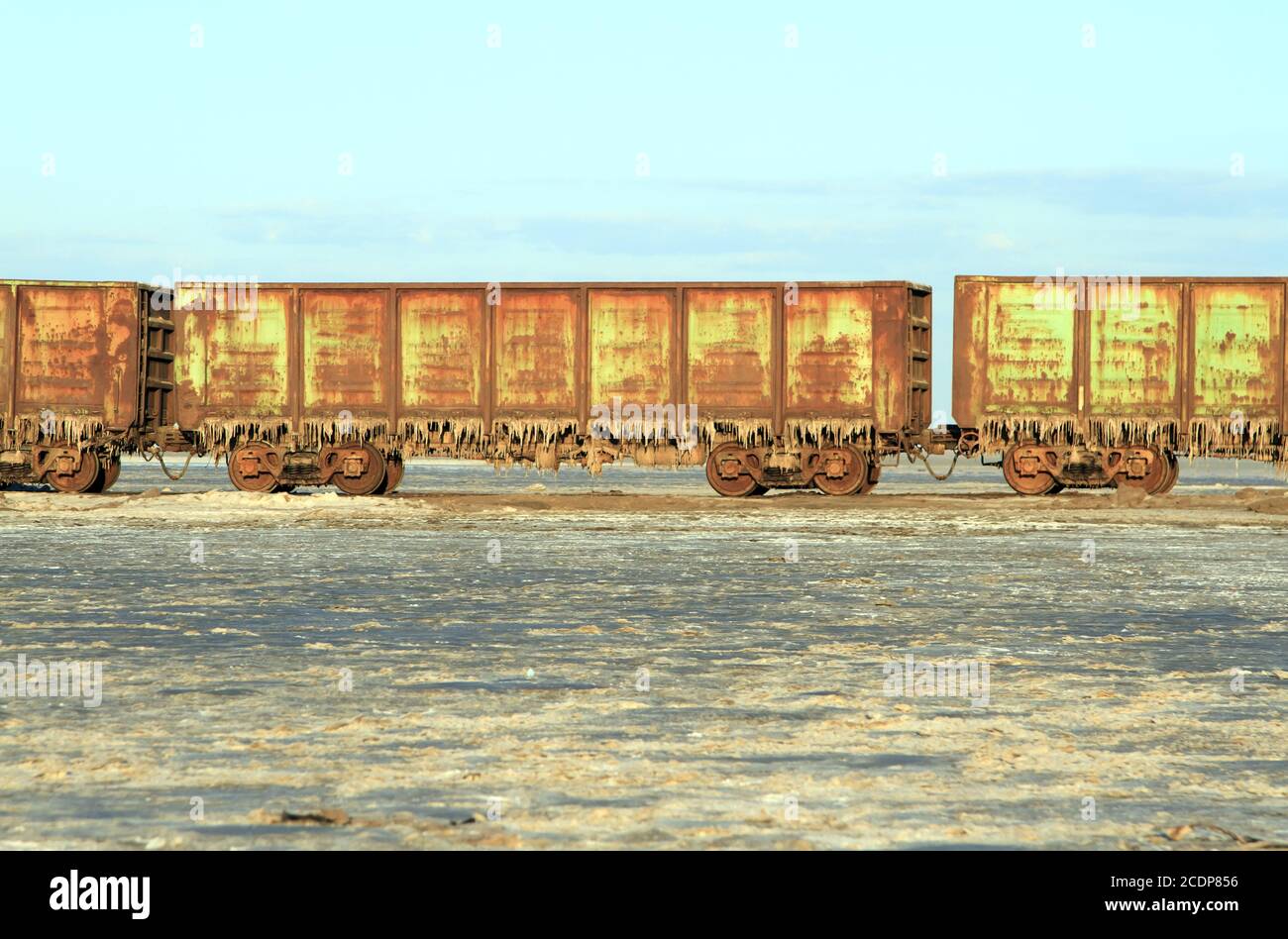 Old rusty train cars with stalactites of salt in the lake Baskunchak Stock Photo