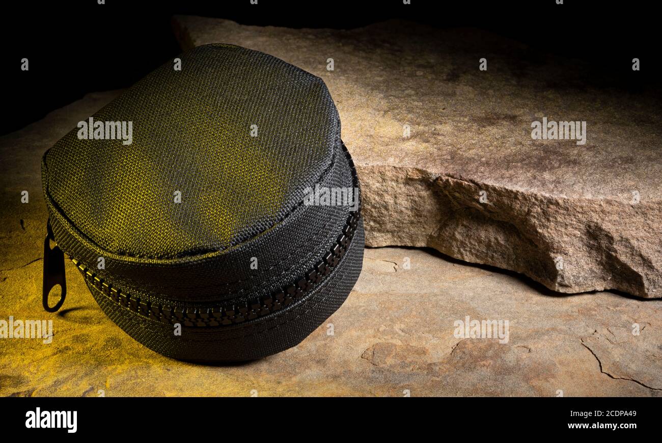 Nylon tactical pouch on rocks with yellow light from the side Stock Photo