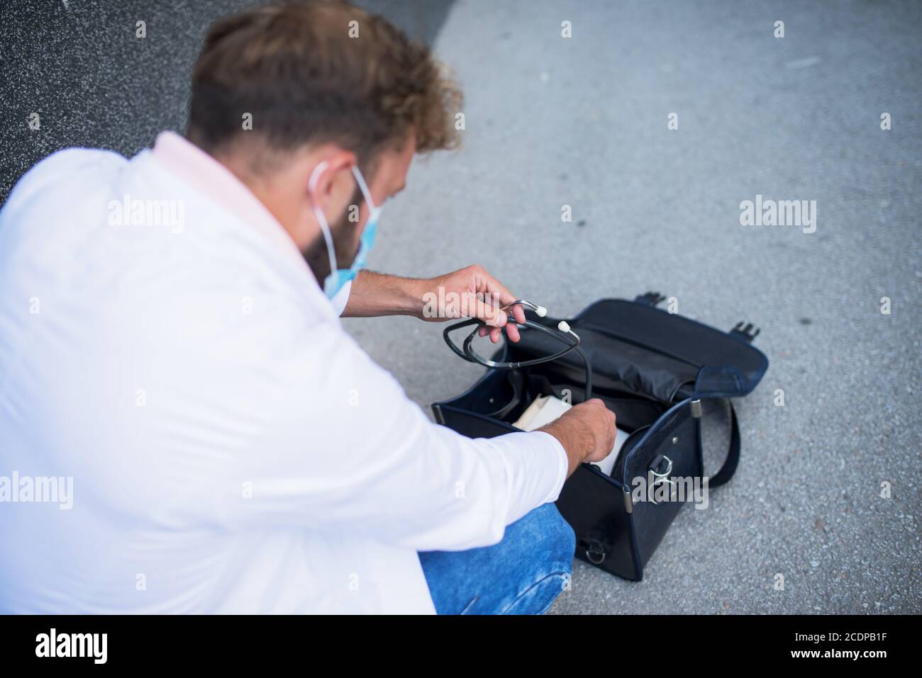 young doctor carrying a doctor's bag and taking out a stethoscope Stock