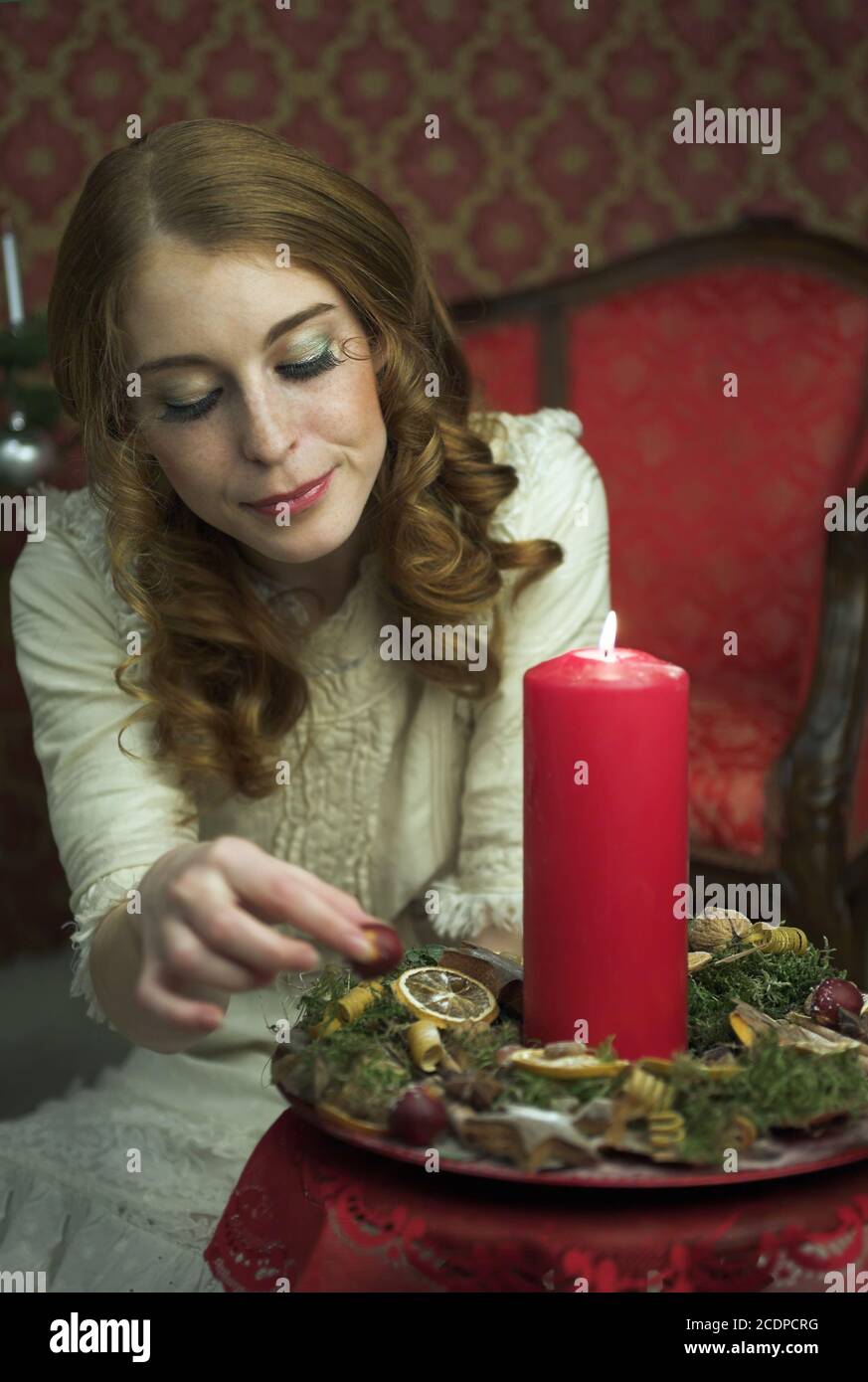 Victorian, historic seeming Christmas scene with young redheaded woman in a antique dress Stock Photo