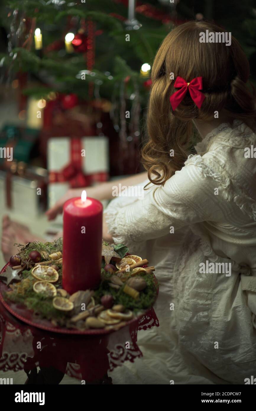 Victorian seeming Christmas scene with young redheaded woman in a antique dress with candle Stock Photo