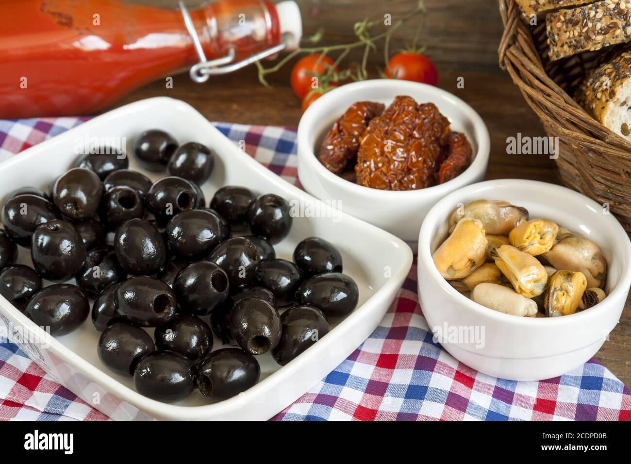 Black olives, sun dried tomatoes and mussels in ceramic bowls Stock Photo