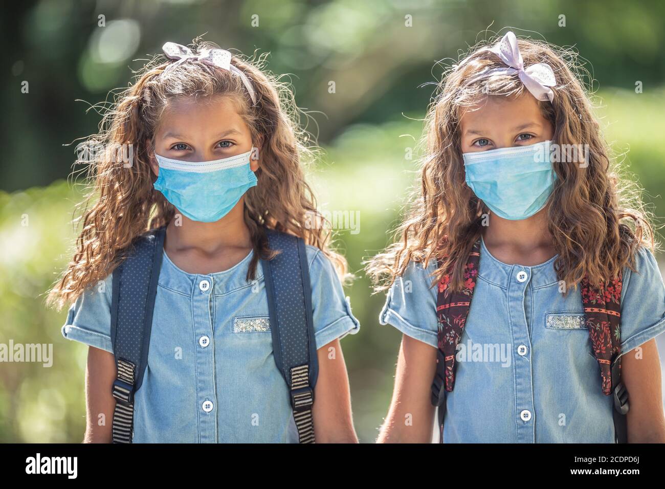 The twin sisters with face masks go back to school during the Covid-19 quarantine. Stock Photo