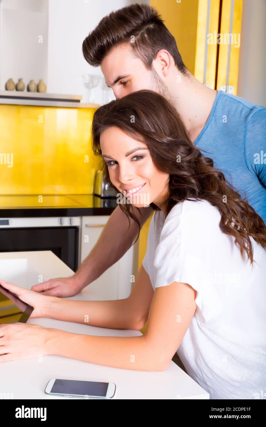 Young couple using a Tablet PC in the kitchen at home Stock Photo