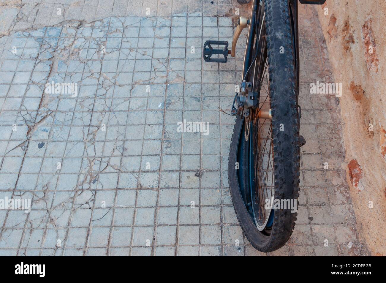 A dark punctured and damaged bicycle wheel on a street with a badly