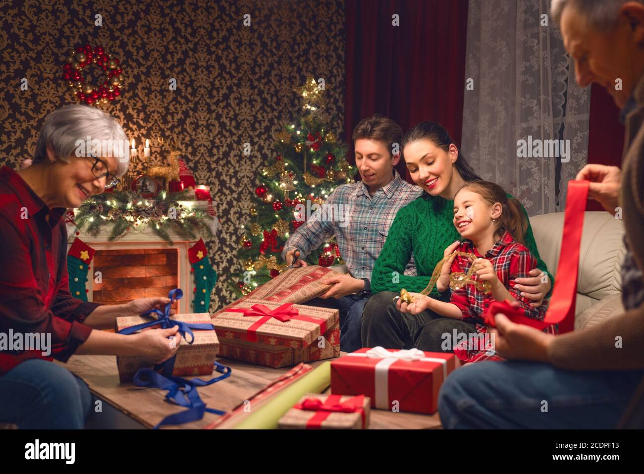 Merry Christmas and Happy New Year! Grandma, grandpa,  mum, dad and daughter near the tree at home. Family preparing for Holiday. Stock Photo