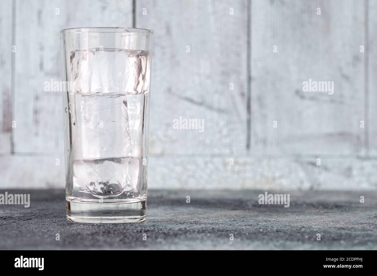Glass with ice cubes on wooden background Stock Photo - Alamy