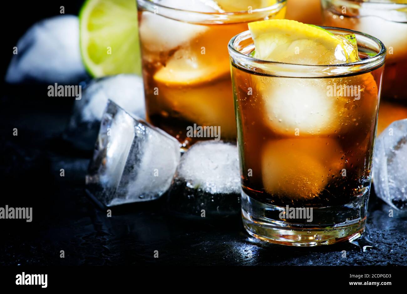 Alcoholic cocktail rum cola with ice, lime, lemon, cola and white rum, dark background, selective focus Stock Photo