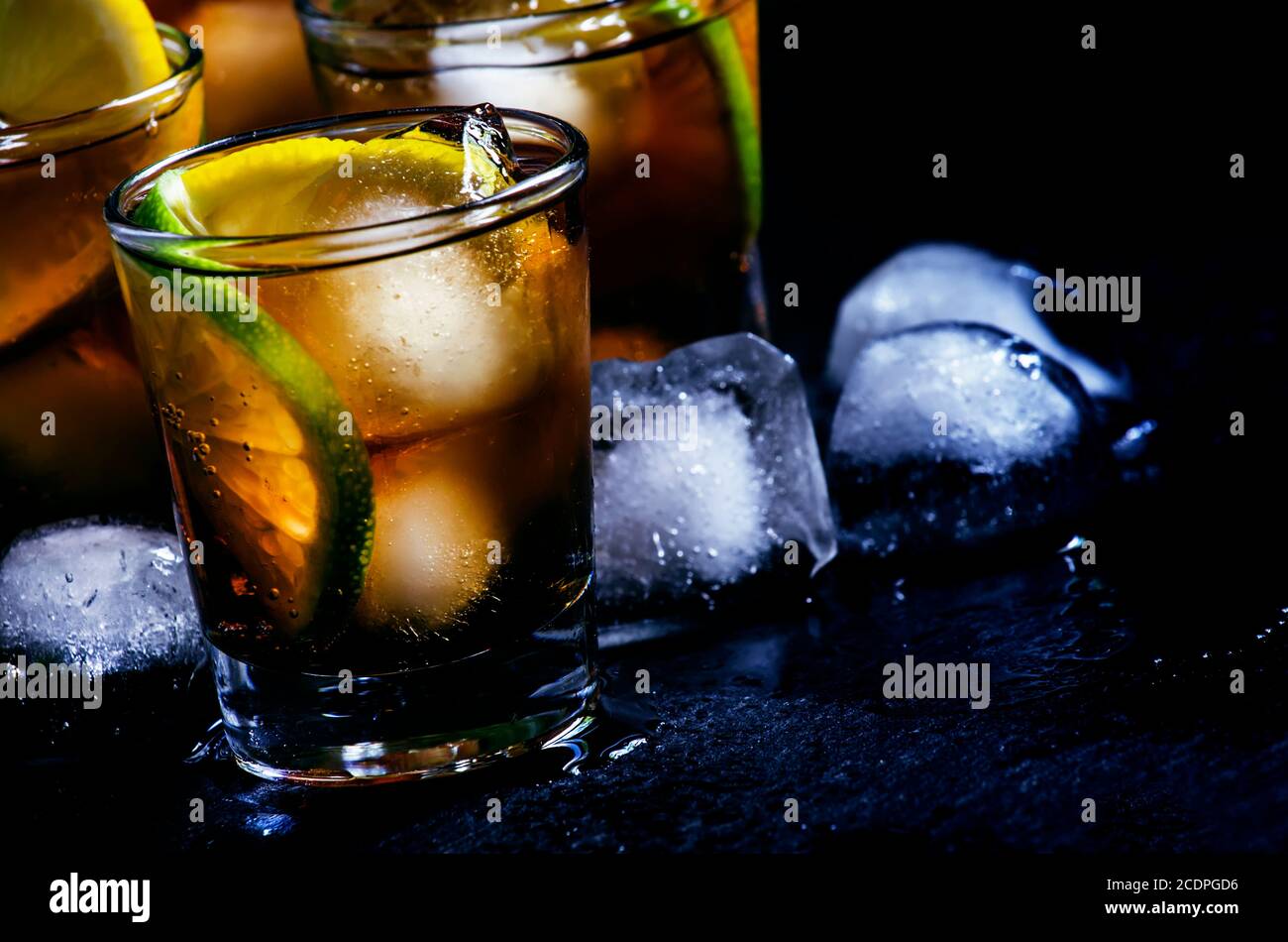 Alcoholic cocktail rum cola with ice, lime, lemon, cola and white rum, dark background, selective focus Stock Photo