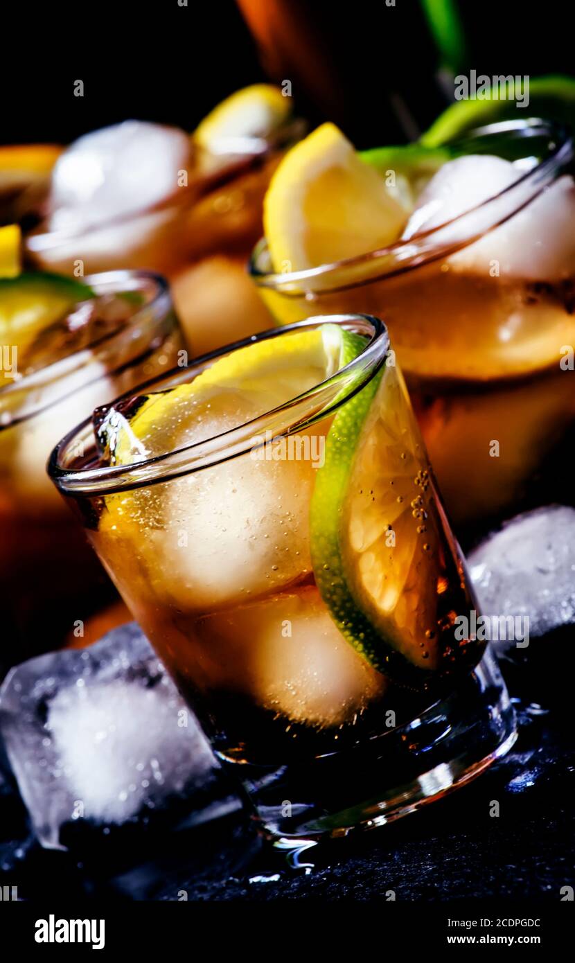 Alcoholic cocktail rum cola with ice, lime, lemon, cola and white rum, dark background, selective focus Stock Photo