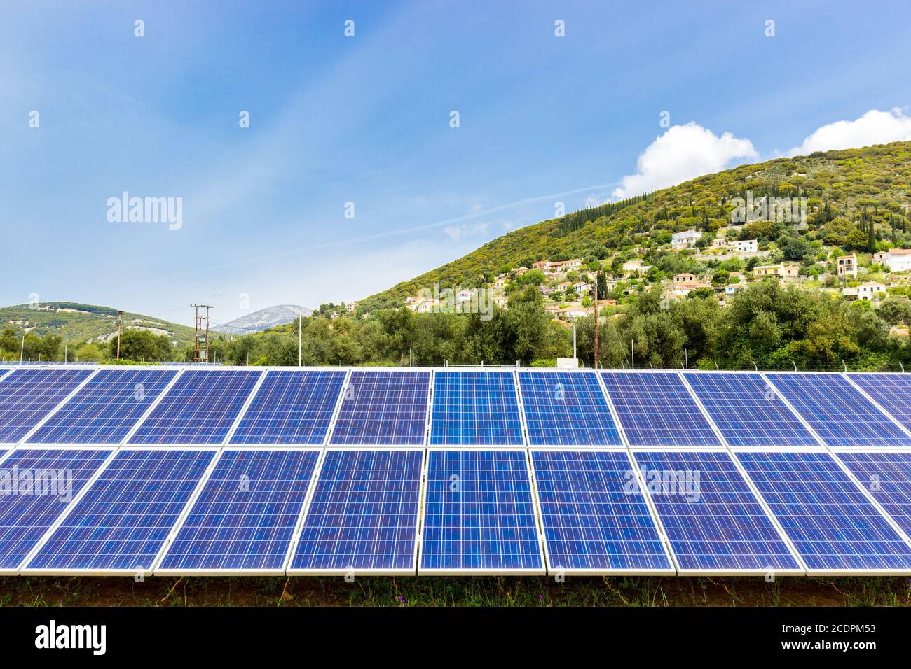 Blue solar collectors near town on mountain Stock Photo